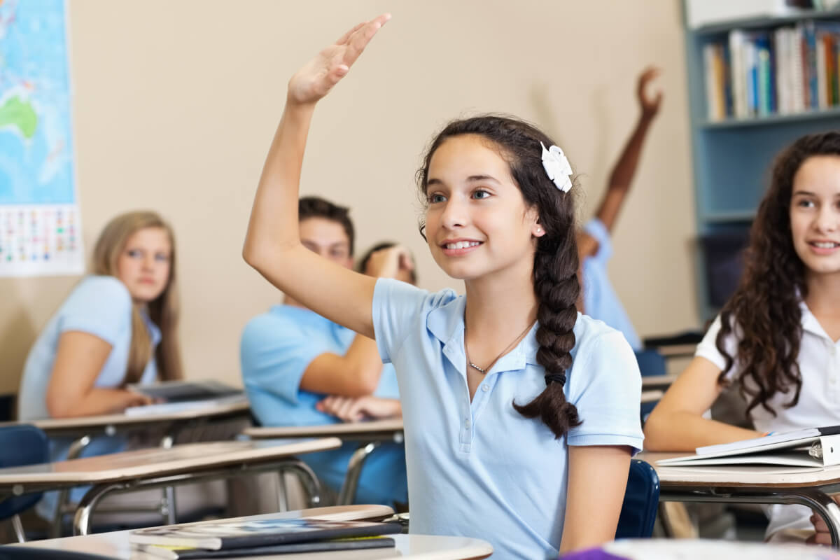 A student raising her hand during a small-class discussion at Wise Owl